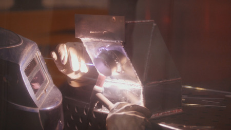 The welder welds metal parts at the plant, industrial plasma welding, modern construction technology