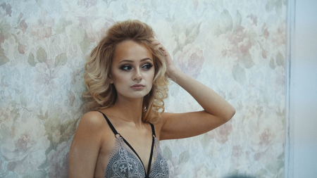 Young blonde model in the underwear posing for photographer during fashion photo sessionの写真素材