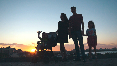 Family at sunset - father, mother, daughter and little son - silhouetteの写真素材