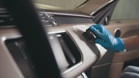 Worker female in gloves is washing with brush a car interior