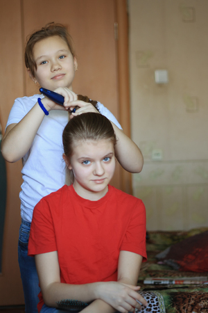 Girls teenagers sisters is making hair for each other at homeの写真素材