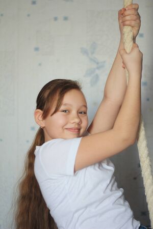 Cute teenager girl 12-years old posing near gymnastic ropeの写真素材