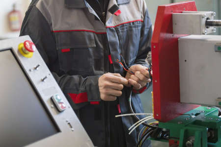 Electrician on overalls is working with energy panel and machinery equipment on plantの写真素材