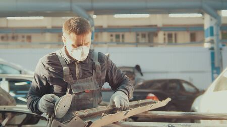 Man worker in automobile service - manual labor - polishes car