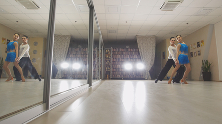 Young attractive man and woman dancing and practicing Latin dance in costumes in the Studioの写真素材