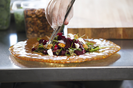 Chef preparing and serving a salad in the kitchen of the restaurantの写真素材