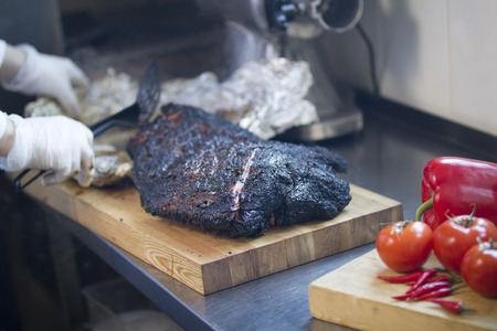Close-up of a large piece of smoked brisket meat on a wooden boardの写真素材
