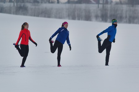 Group of athletes warming up and stretching before exercise in winter forest