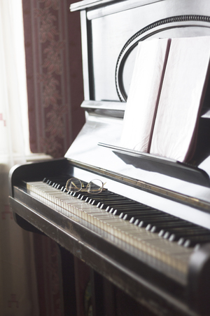 Old piano with sheet music and spectacles lying on the keyboardの写真素材