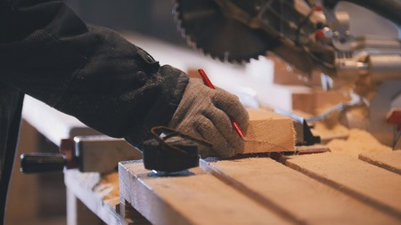 Worker carpenter figuring wooden board before circular saw sawingの写真素材