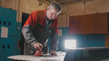 Manual sander sanding a metal detail at the factory