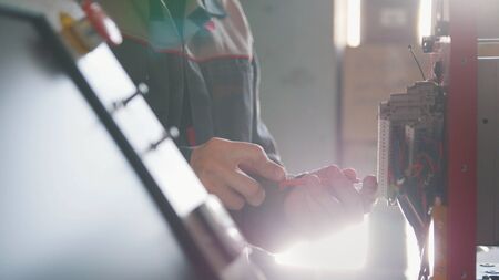Electrician male in overalls is working with energy panel and machinery equipment on plantの写真素材