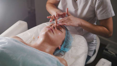 Woman doctor performes cosmetic procedure - mask facial massage at spa salon skincareの写真素材