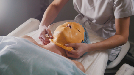 Close up of a face of beauty salon visitor, fruit mask is applied on the face with a special wooden stickの写真素材