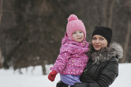 Mom and her daughter in the winter street, the woman holding the girl in her arms