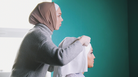 Muslim woman tying Islamic turban for attractive brideの写真素材