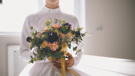 Beautiful muslim bride holding bouquet of flowers in handsの写真素材