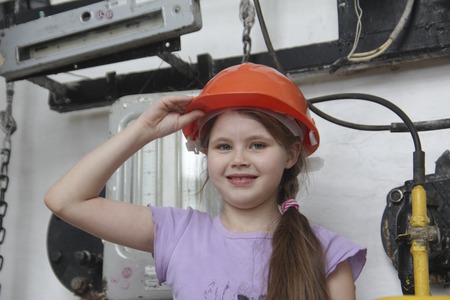 A little girl is playing with red construction helmetの写真素材
