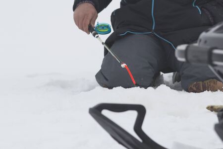 Fisherman on ice fishing caught fish at lake