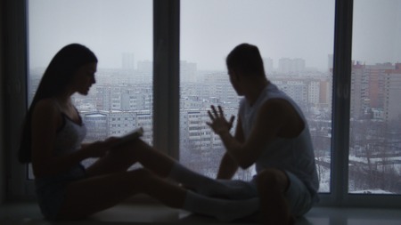 Family couple sitting on the windowsill and spending time at homeの写真素材