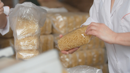 Workers packaging raw macaroni from the production line in a pasta manufacturyの写真素材