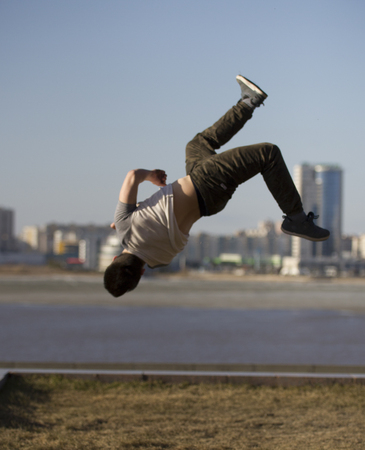 Young man parkour sportsman performs back tricks in front of skylineの写真素材