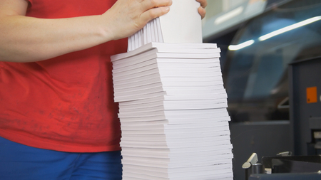 Hands of female worker folds a paper stacks in typographyの写真素材