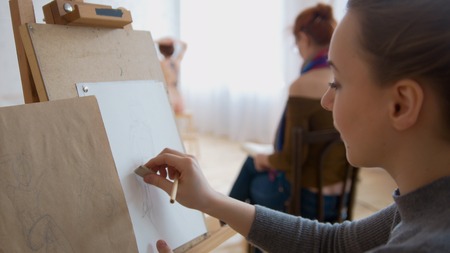 Young female painter draws sketches in drawing studioの写真素材