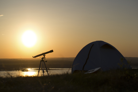 Tent with telescope stands on the hill under sunsetの写真素材