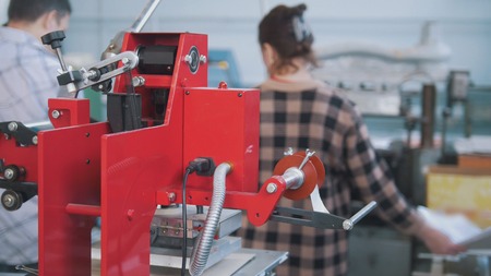 Printing press equipment in front of people working in typography