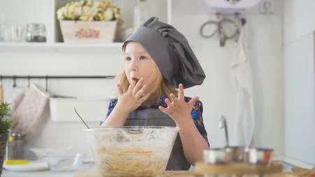Preschool girl baker mixes the dough in a bowlの写真素材
