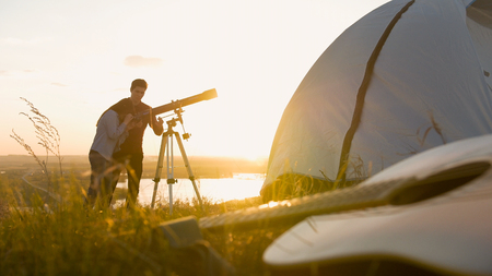 Guitar on grass in front of young couple enjoying summer vacation outdoors at sunsetの写真素材
