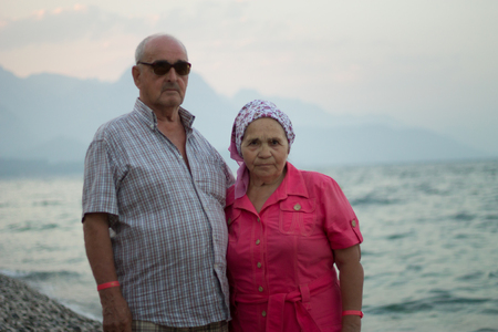 Portrait of elderly caucasian couple by the sea on background mountainsの写真素材