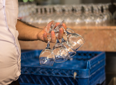 Bartender hand holds the lots of wine glassesの写真素材