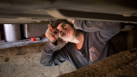 Male mechanic underneath a car working on the repair of the car
