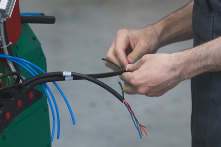 Hands of electrician works with electric wiresの写真素材