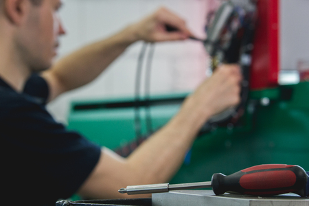 Hands of electrician engineer screwing and testing equipment in fuse box, de-focused