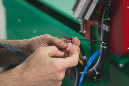 Electrician works with parts of energy equipment on plantの写真素材