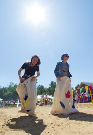 KAZAN, RUSSIA - JUNE 23, 2018: Traditional Tatar festival Sabantuy - Young women having fun playing traditional game, jumps in bags under the sunのeditorial素材