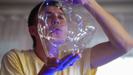 Artist blow out big soap bubbles and holding them