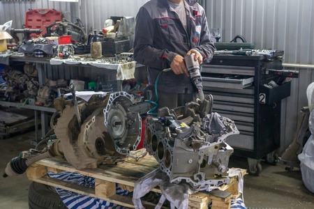 Mechanic repairs the engines valve block of the car in a car-care center