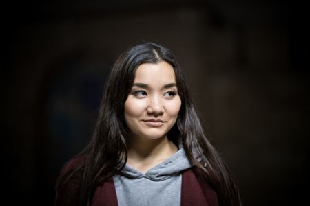 Portrait of young woman on a black background. Looking to the sideの写真素材