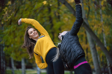 Autumn photo of sporty women stretching and doing yoga in forest at morning against background of trees.の写真素材