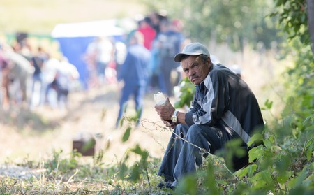 20 August 2018, Krasnovidovo, Russia - sullen old man sitting on the grass. folk fairのeditorial素材