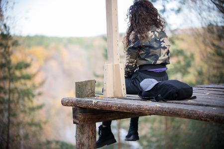 Young woman sitting on a platform on a background of the forest. Back viewの写真素材