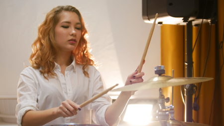 Pretty redhead girl playing drums in studioの写真素材