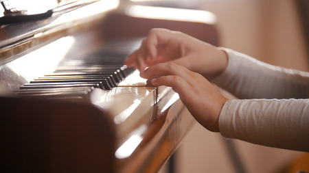 A little girl hands playing piano on music lesson in schoolの写真素材