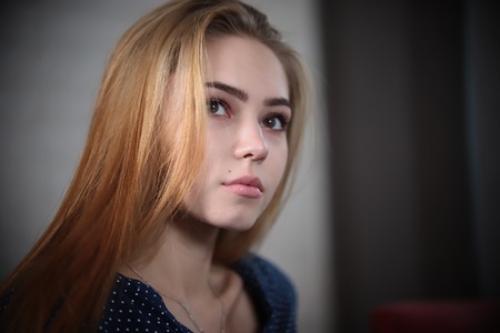 Portrait of beautiful young woman with blonde hair looking above the camera over lights in background.の写真素材