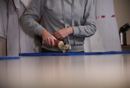 Cutting the cloth by sketching using the instrument. Hands close upの写真素材