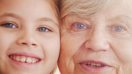 Close up portrait of grandmother and granddaughter. Looking in the camera, smilingの写真素材